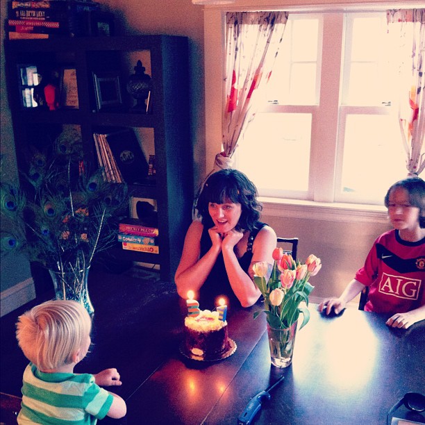 a woman with children around a table with a cake