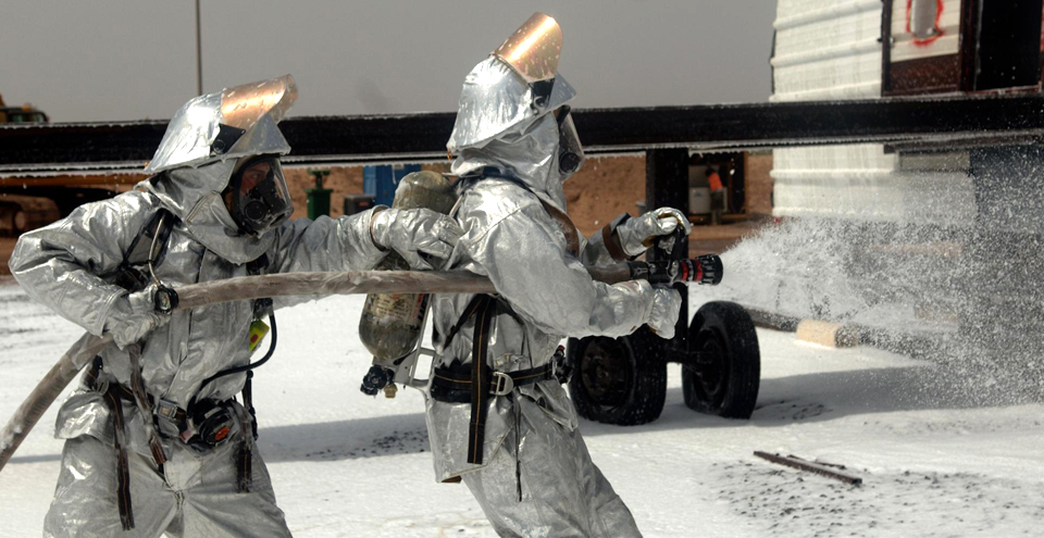 two people in gas suits throwing out water onto the ground