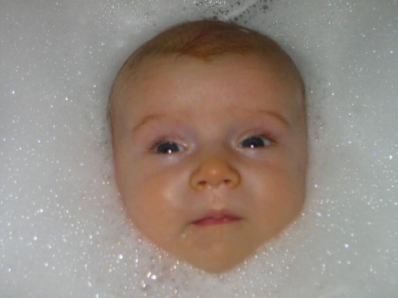 a baby laying in the bathtub with bubbles all over its body