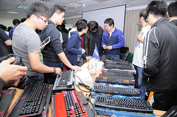 people standing around an open laptop computer on a table