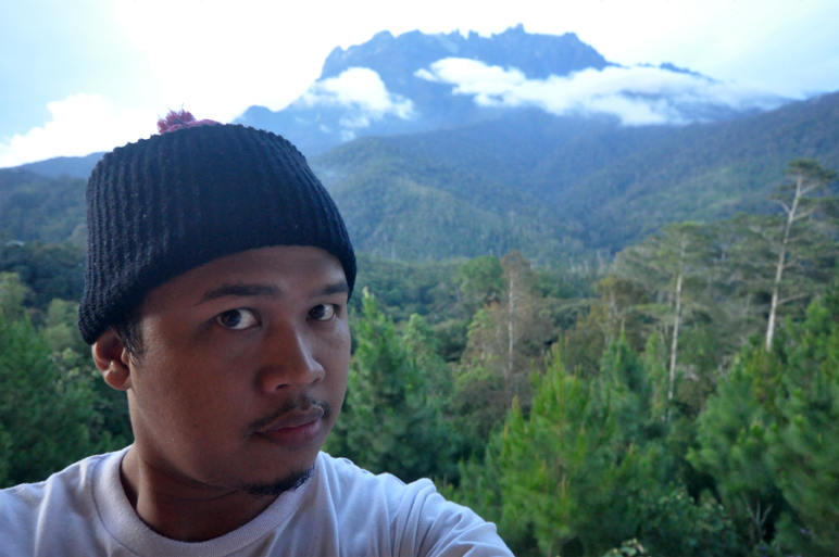 a man with a cap on in front of trees