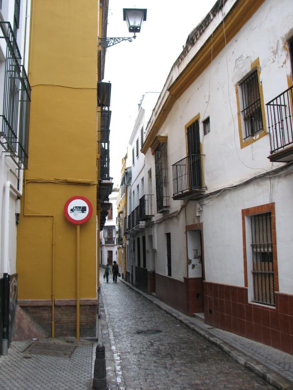 people are walking on an old street with narrow buildings