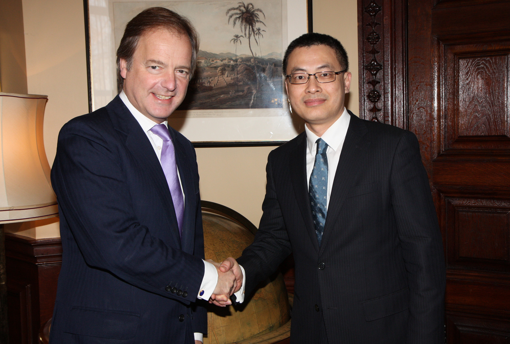 two men shaking hands inside of a living room