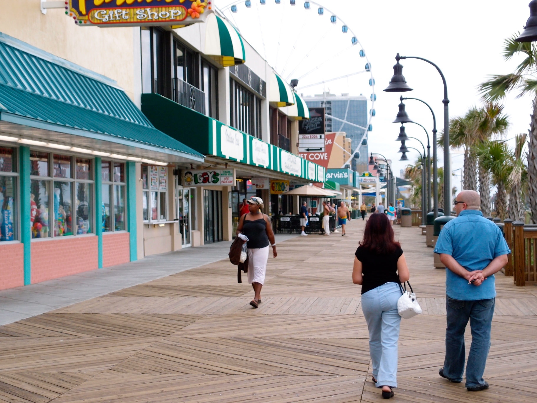 people walking on the boardwalk near shops and stores