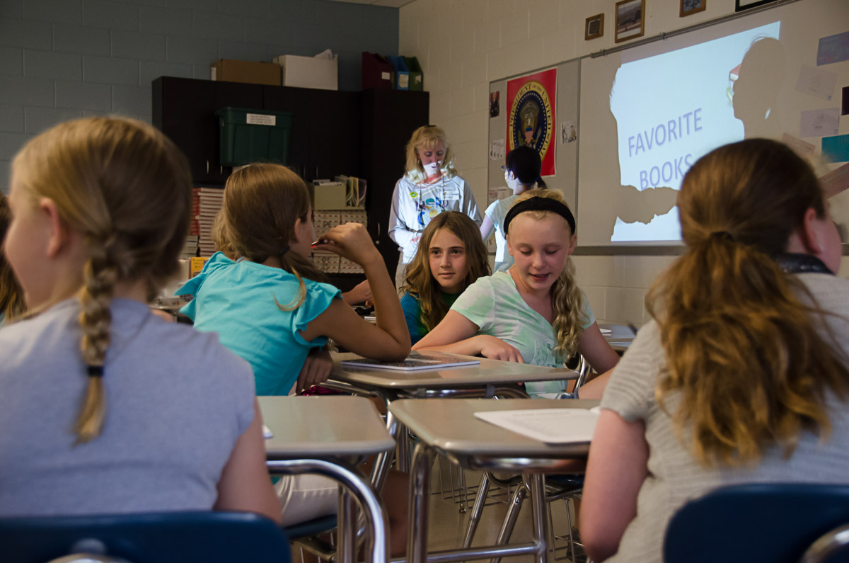 a group of s and adults sit in classroom with their teacher