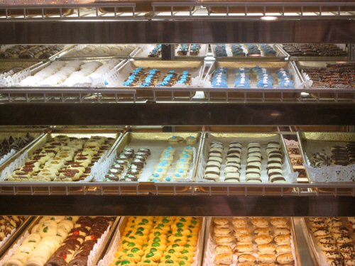 an assortment of cookies, desserts and pastries are in glass cases