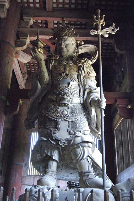 a large statue stands in an ornate wooden structure