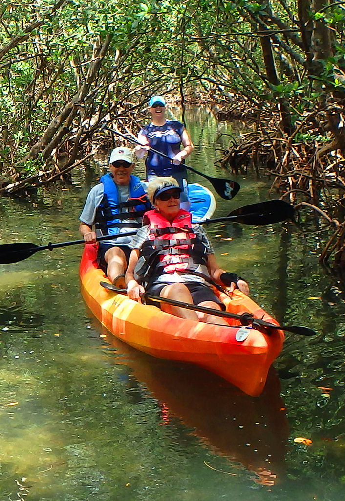 three people are in orange boats floating on the water