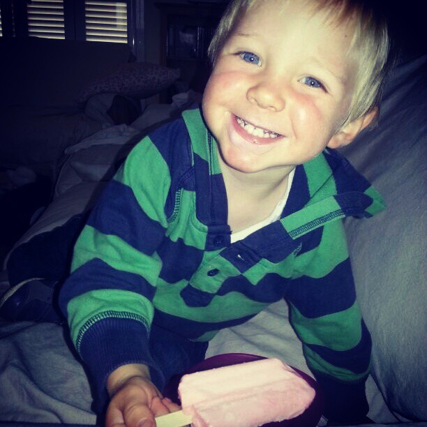 a boy smiles as he holds a large piece of ice cream