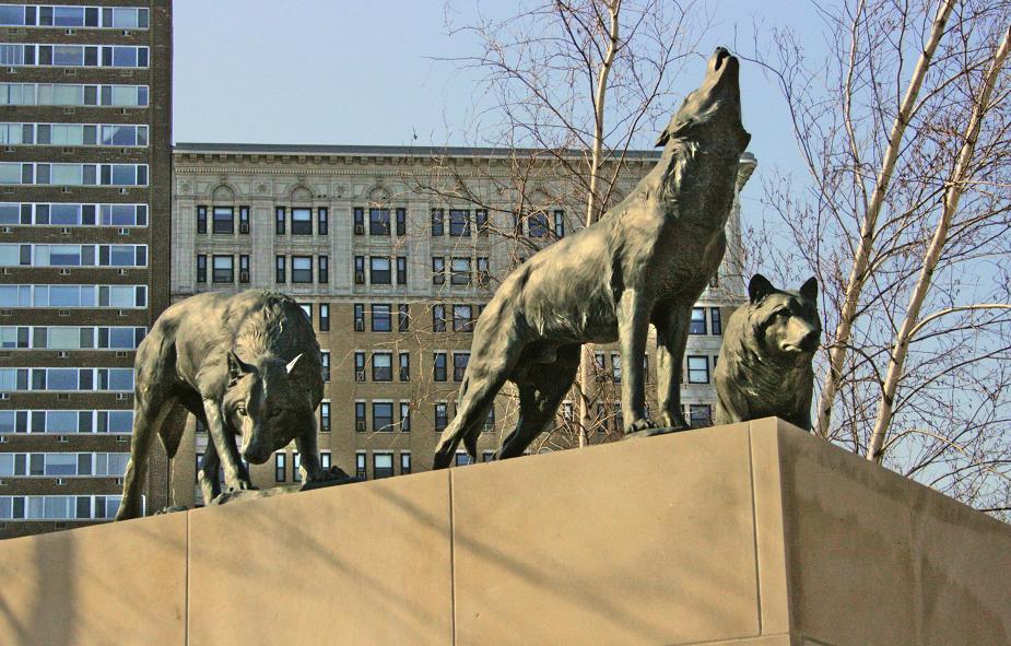 three dogs on top of a statue outside a city building