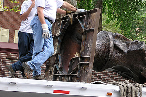 two men that are standing on the back of a truck