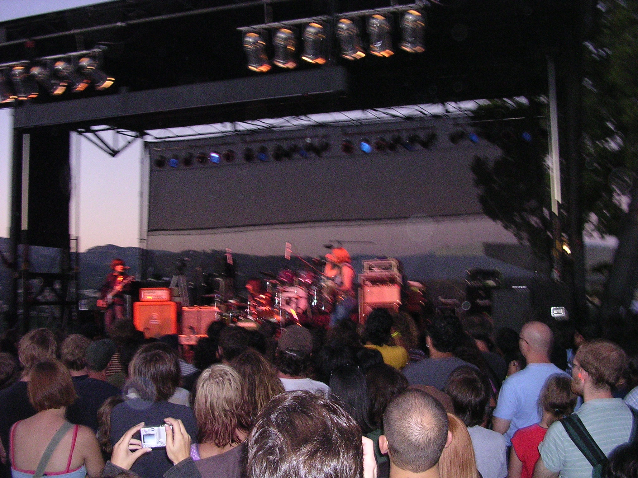 an outdoor concert in the evening with people looking up at a stage