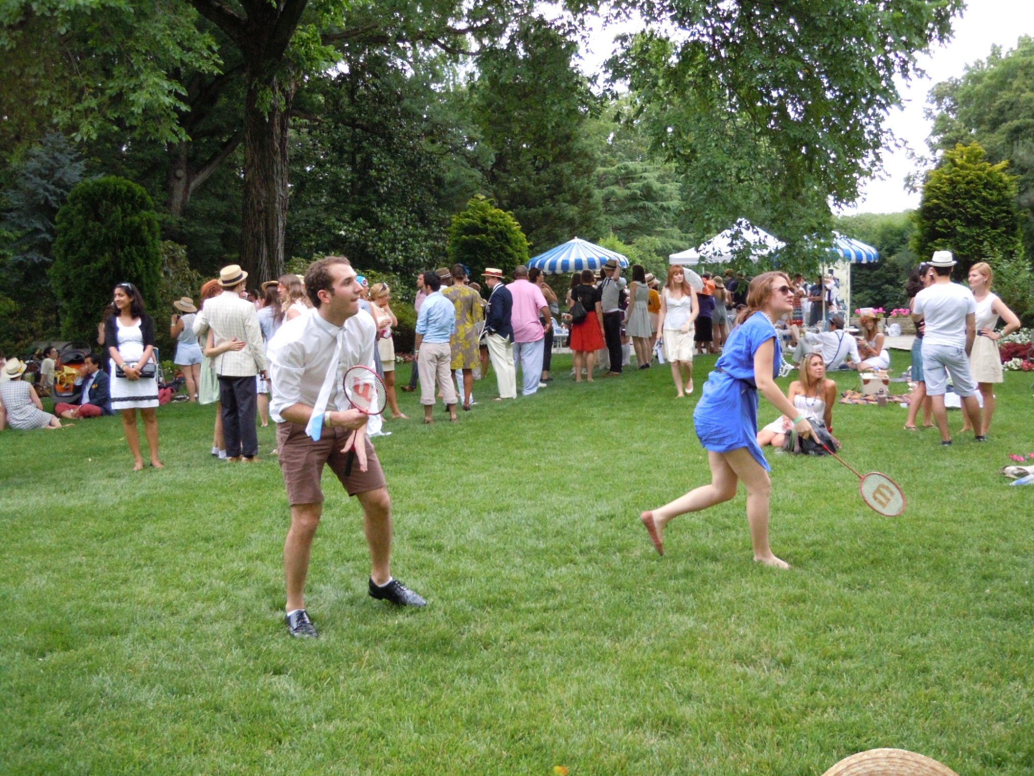 two people with frisbees in grassy field next to trees