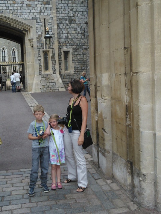 a woman and two boys stand beside an old castle