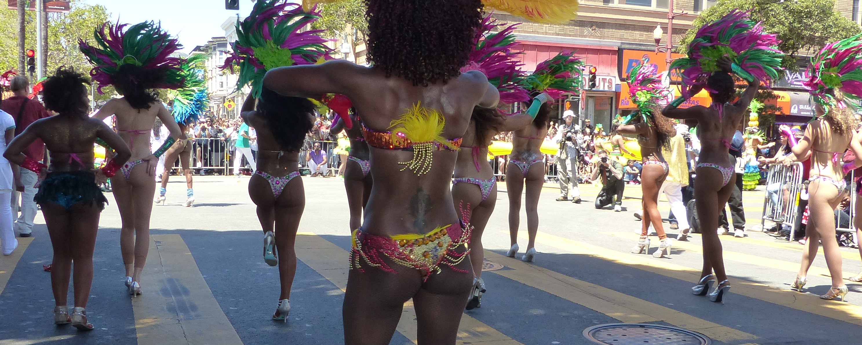 a parade with many dancers, including in costume, carrying large umbrellas