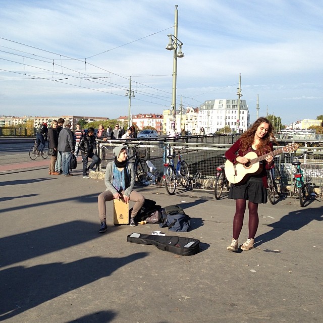 a woman standing on a street holding a guitar