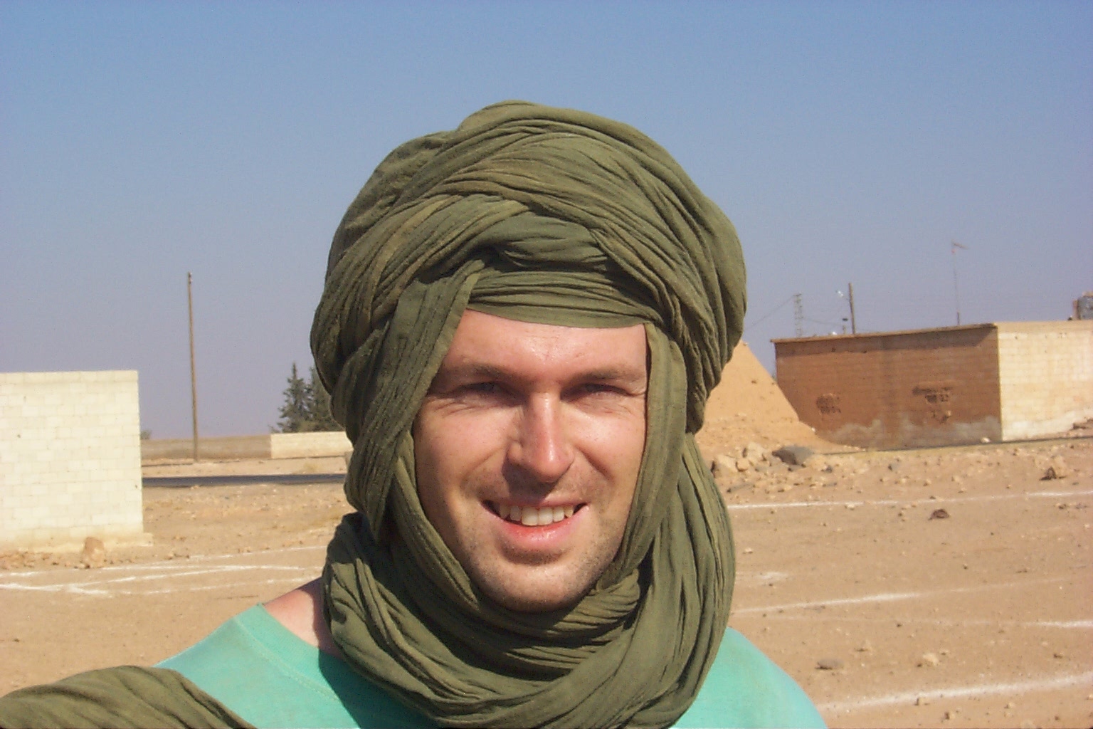 the man is dressed in green shawl with a smile