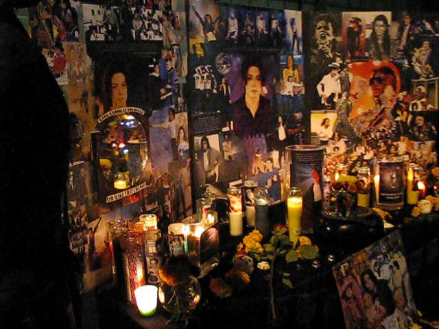 a wall full of pos with candles, pictures, and flowers