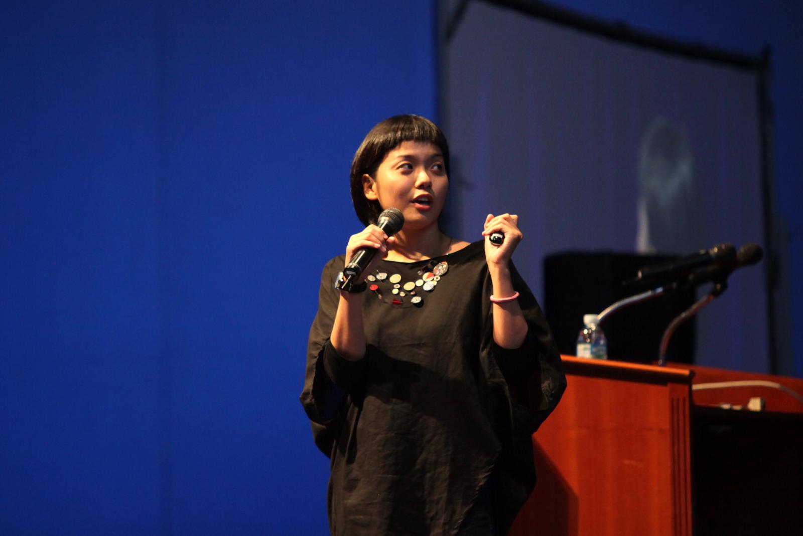 an asian woman speaking into a microphone at a podium
