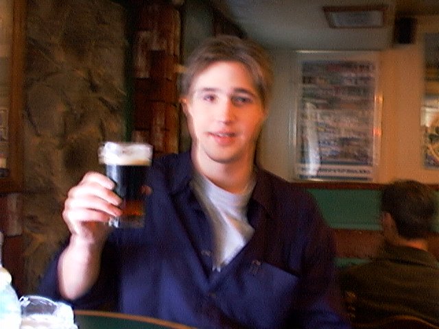 a man sitting in a pub with a pint of beer