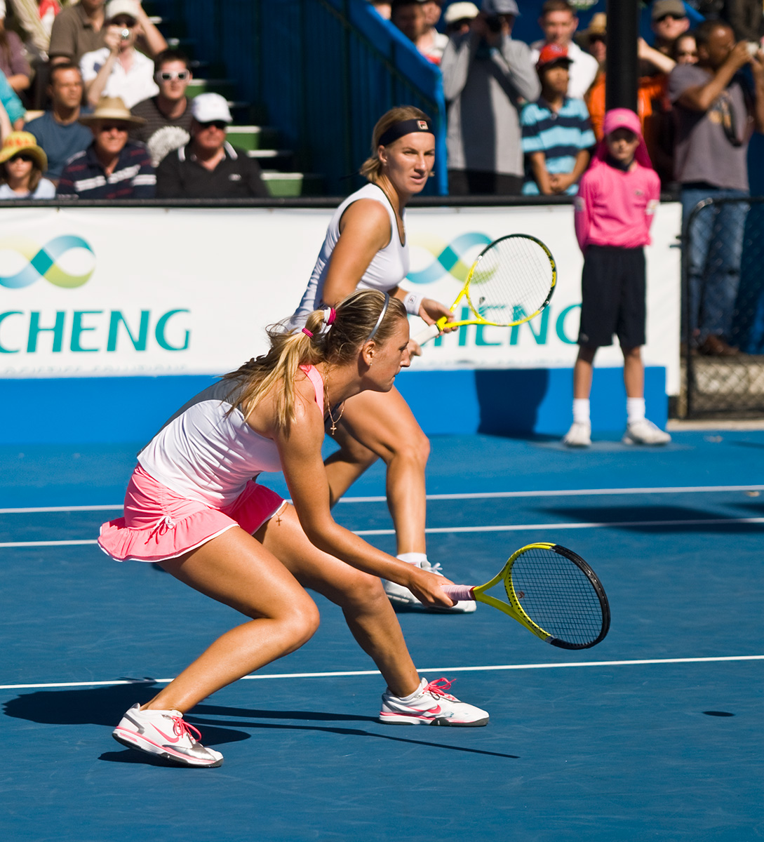two young women on a tennis court preparing to play