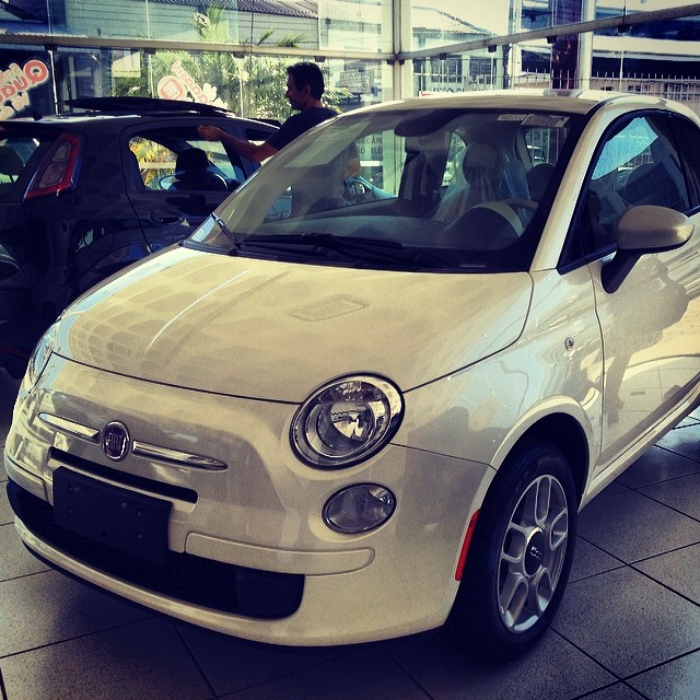 small white car in showroom being shown from the front