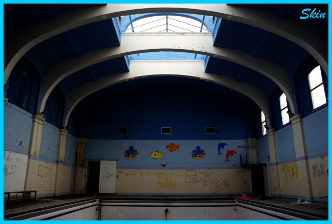 an empty swimming pool in a building with graffiti on the walls