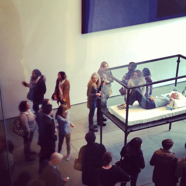 a group of people observing and viewing a bed in an open room
