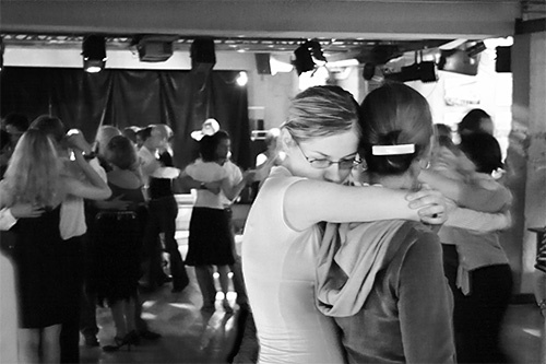 two women hugging each other while people dance in the background