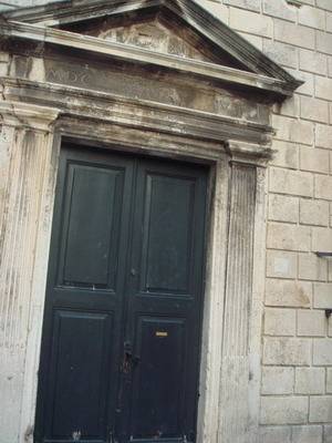 an old building that is painted black and has a stone front wall