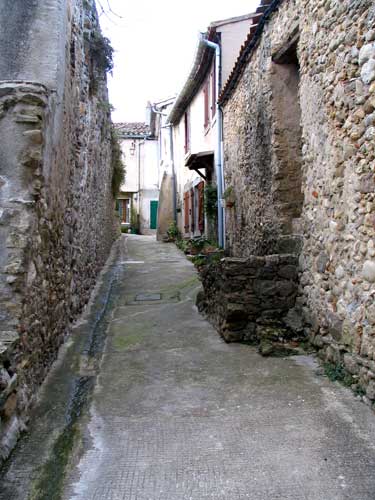 a narrow paved street between two stone buildings