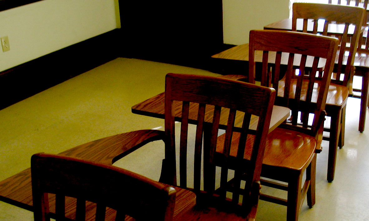 wooden chairs sit next to each other in a large room