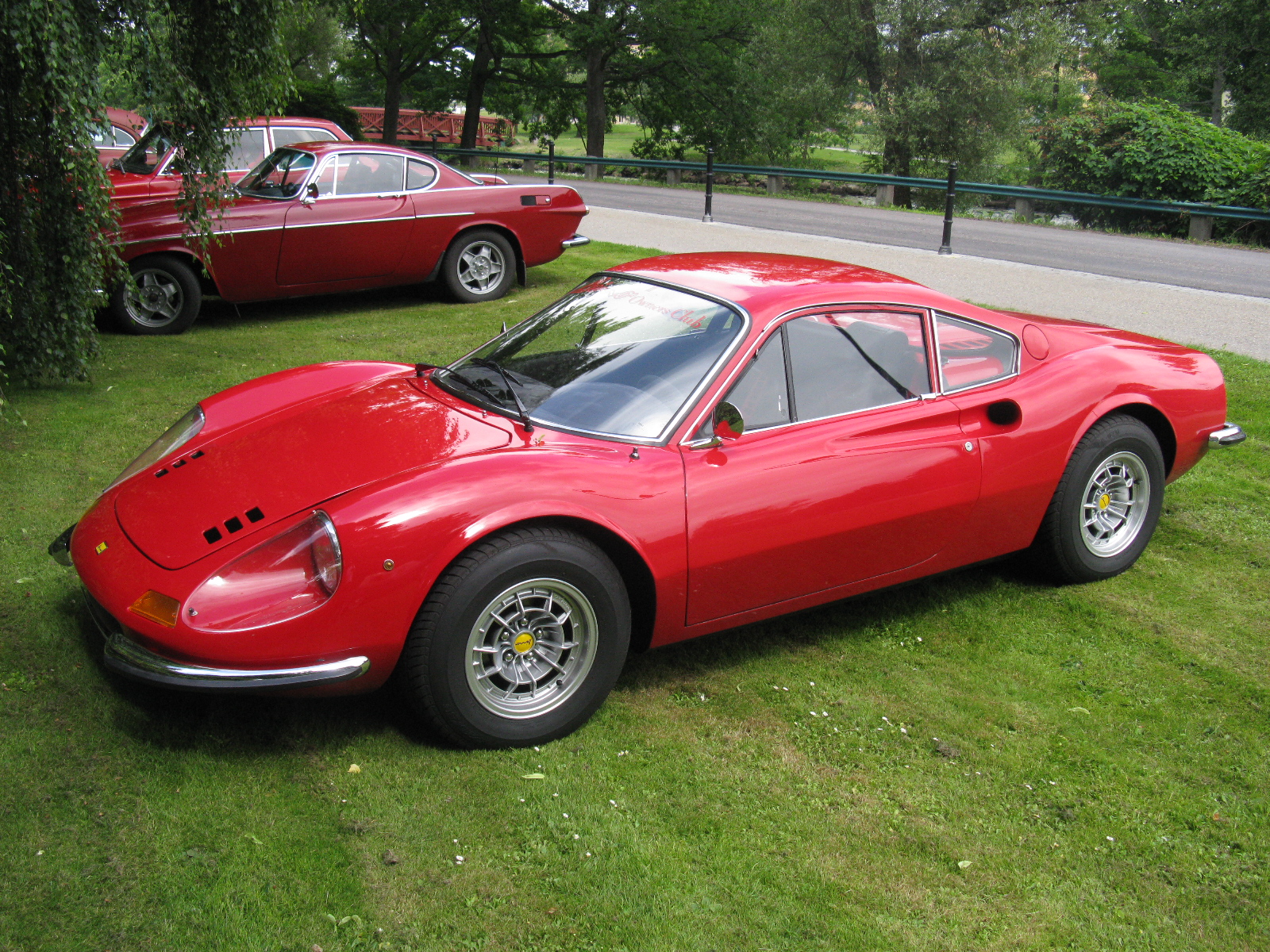 two very nice looking cars parked in a grassy field