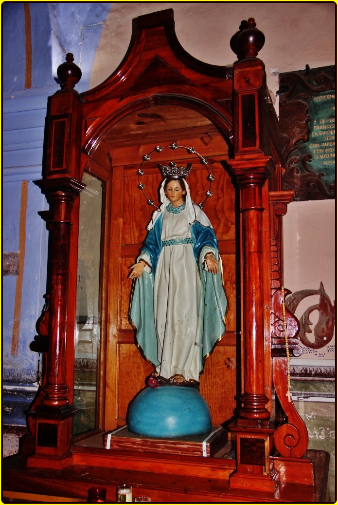 the statue of mary, sitting on a bed in the corner