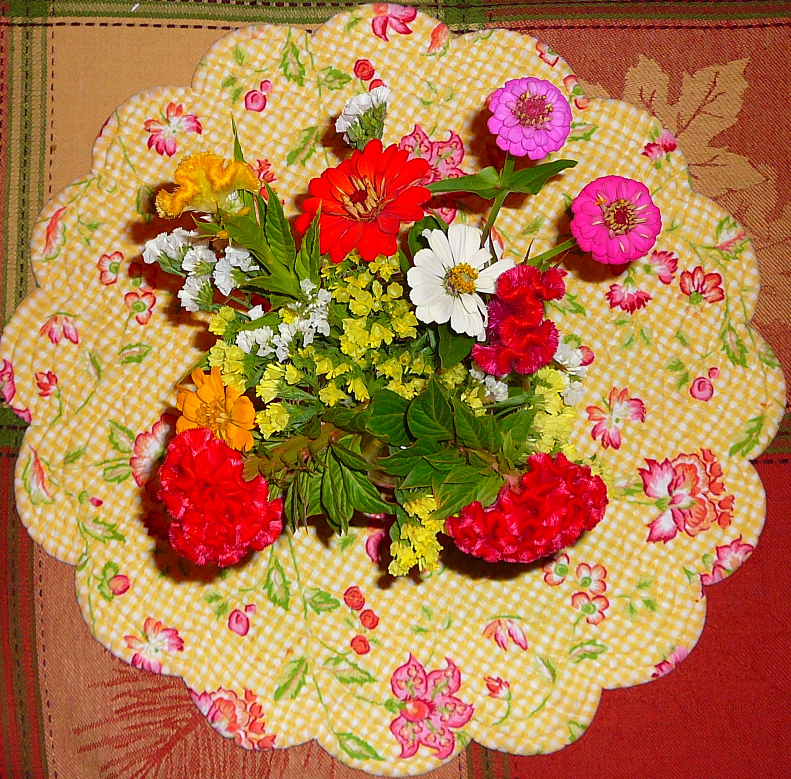 a vase full of colorful flowers sitting on a yellow and white checkered tray