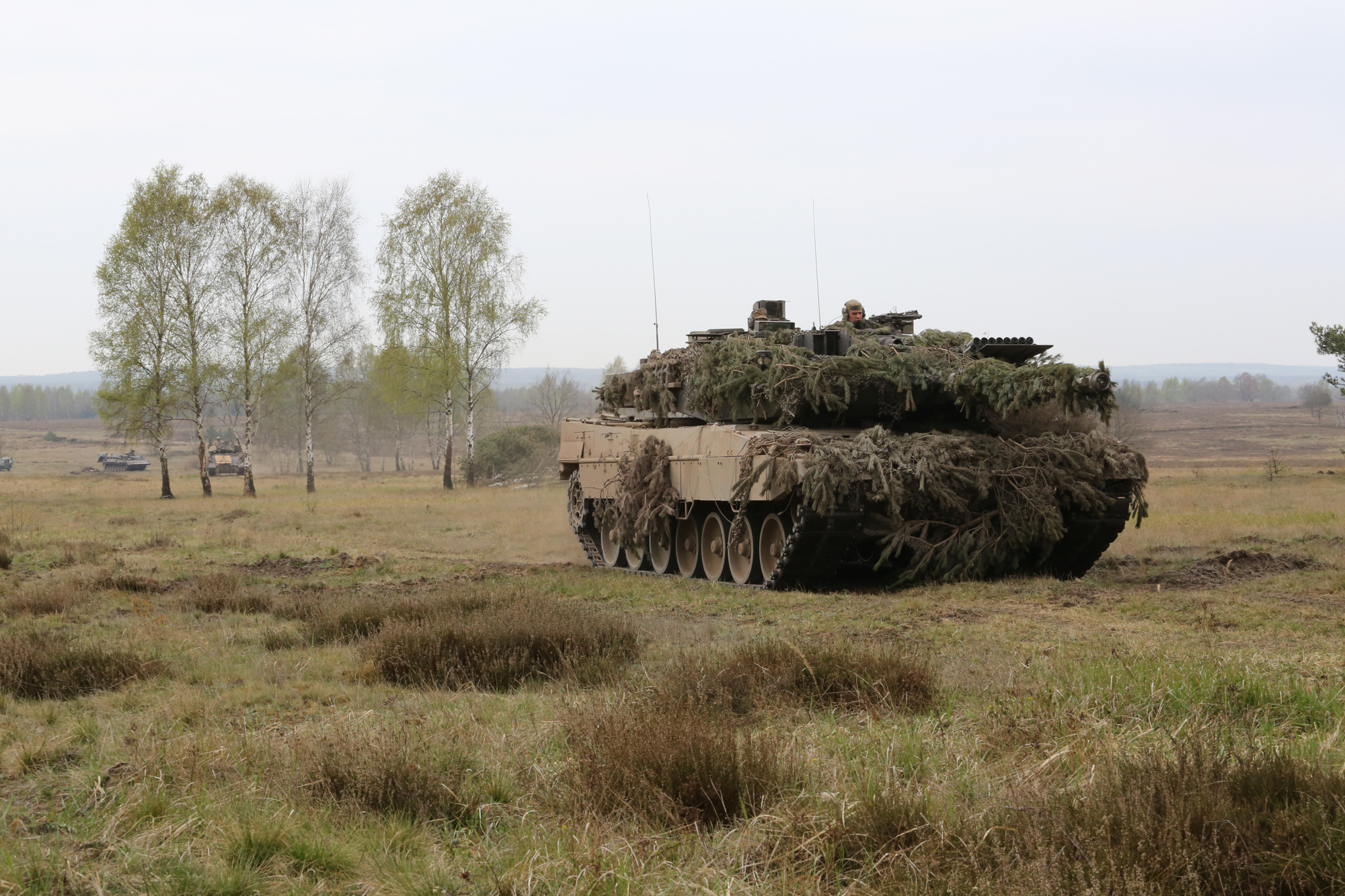 an old military tank covered with camouflage in the field