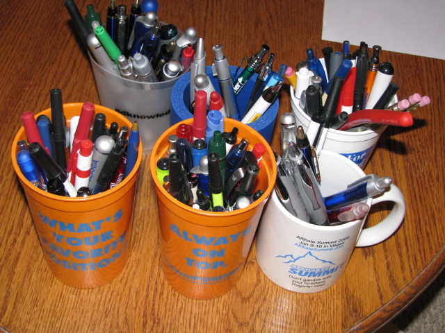 a close up of a cup with pens and pencils in it