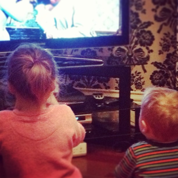 two s playing with wii remote controls in front of a tv