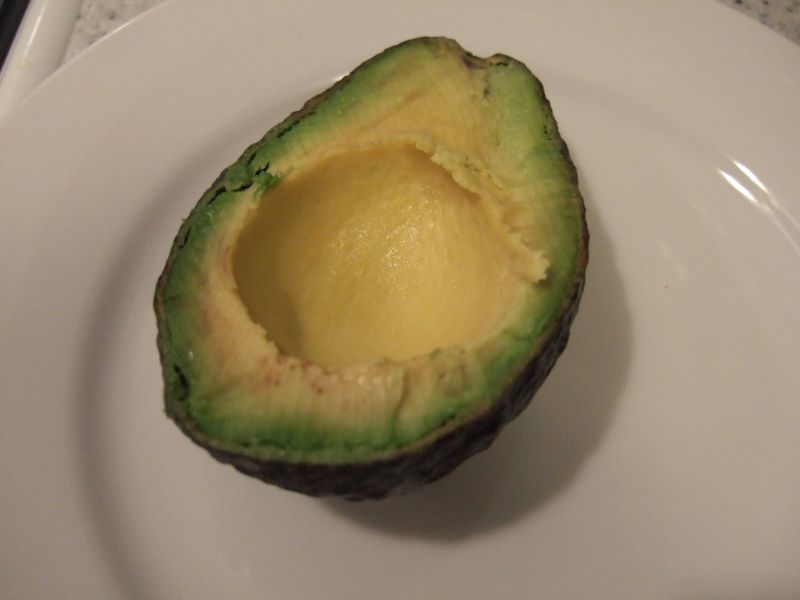 a small avocado cut in half on a white plate