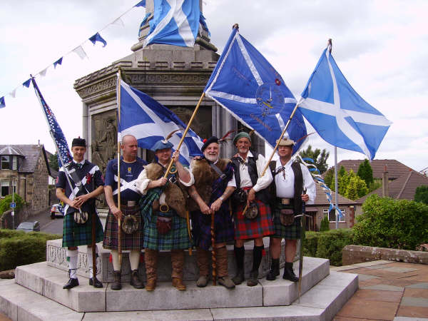 a group of men and women standing around a monument holding flags