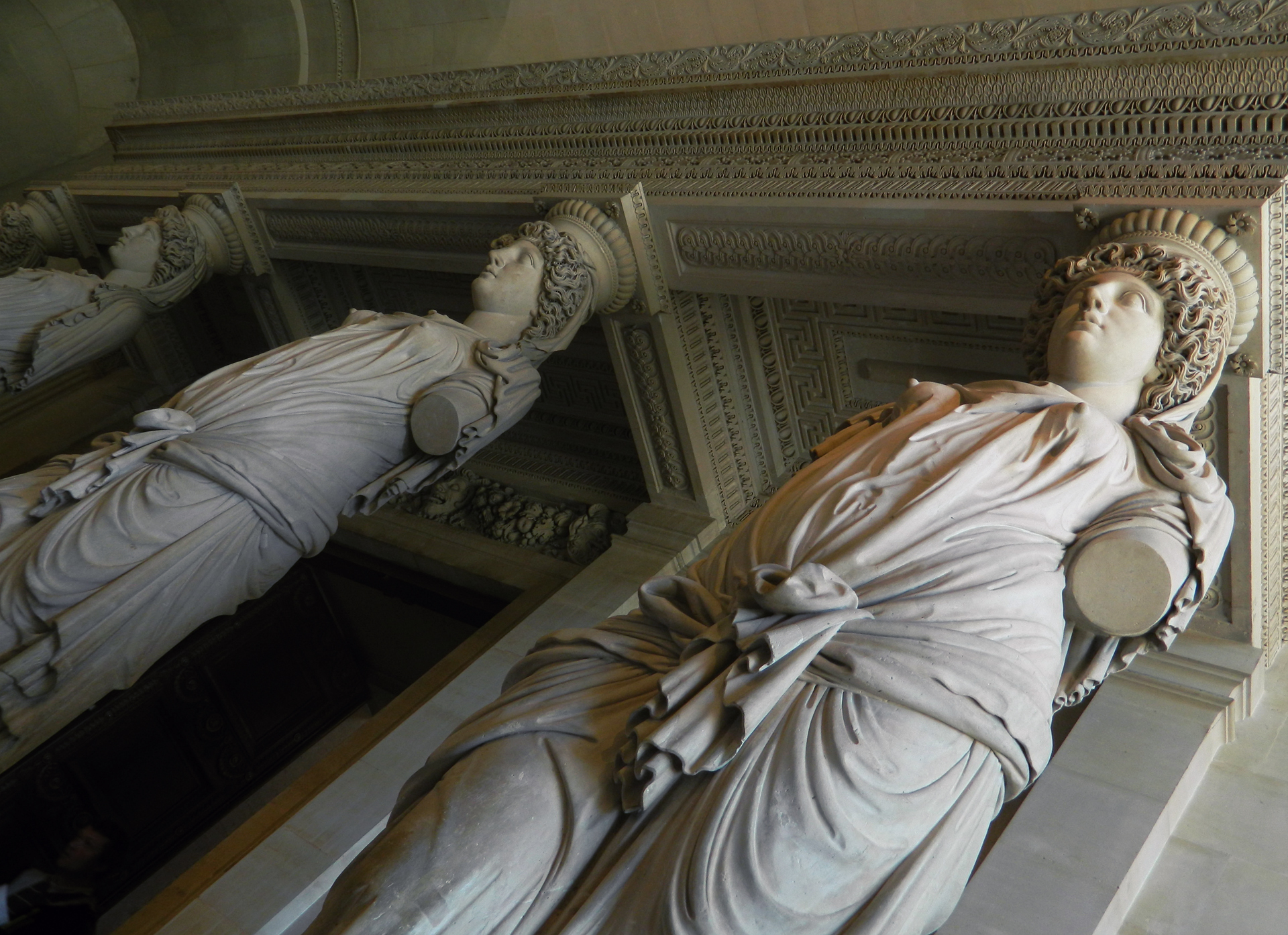 statue of woman standing in a room between pillars