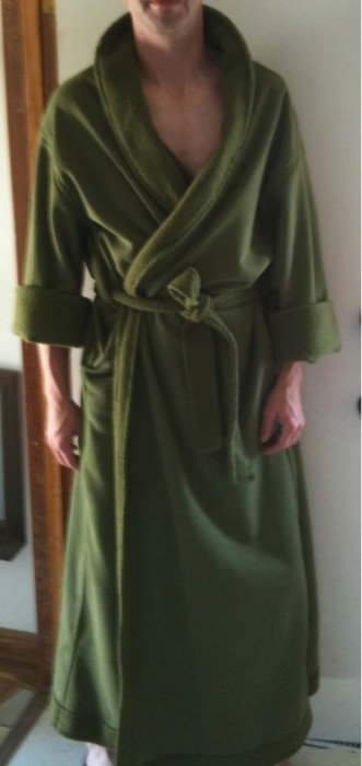 man in green robe with socks on standing near mirror