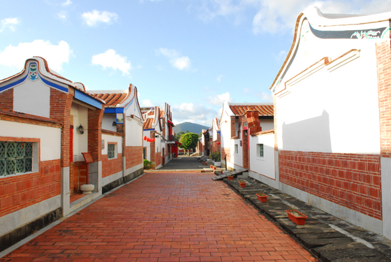 a long red brick paved road between two buildings