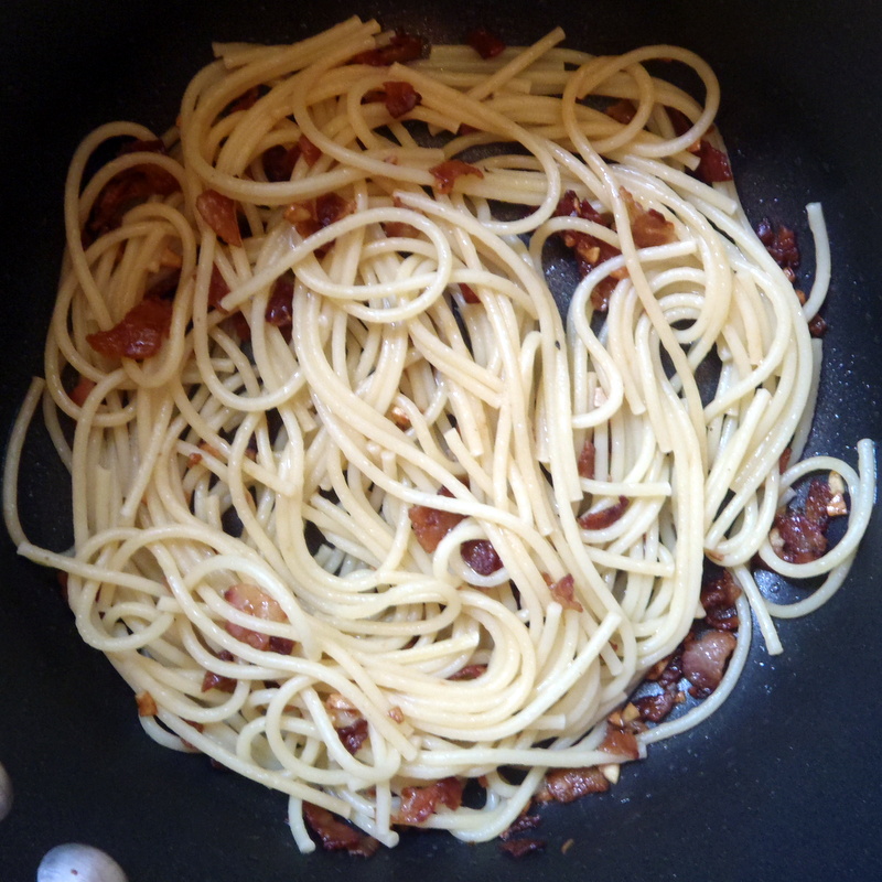 noodles being cooked in the black pan