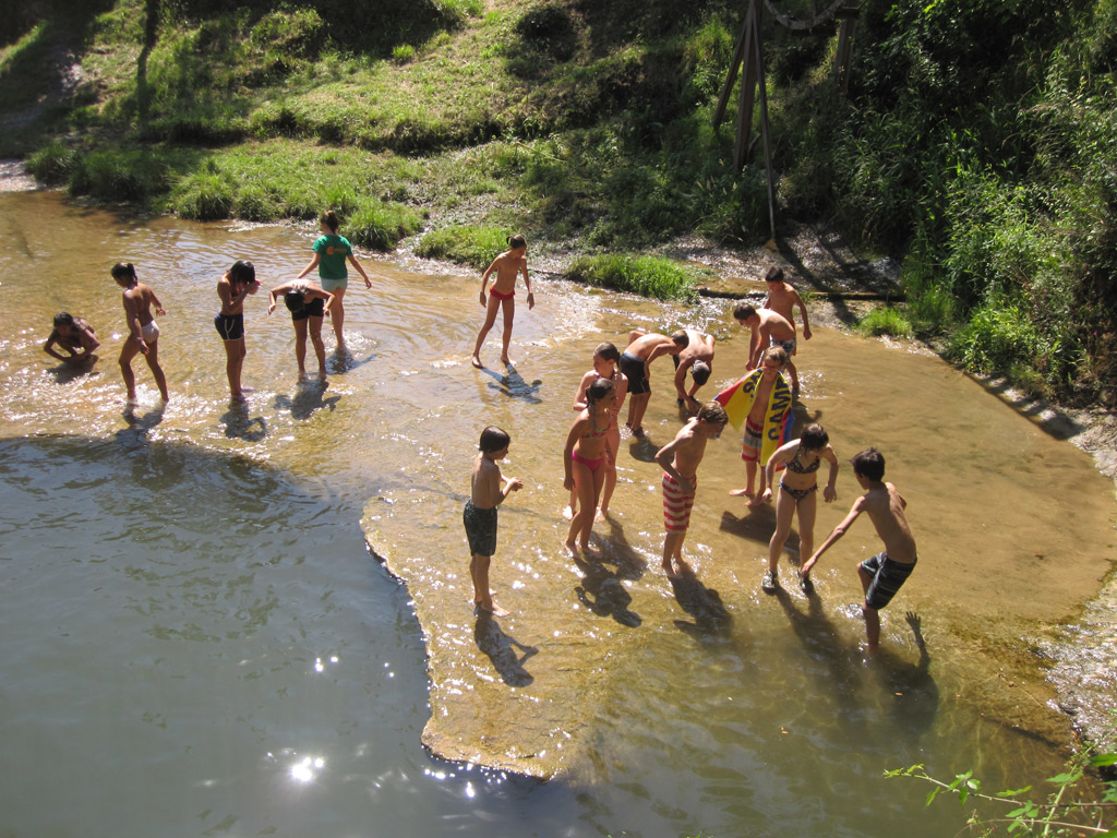 young children are playing in the water near a small river