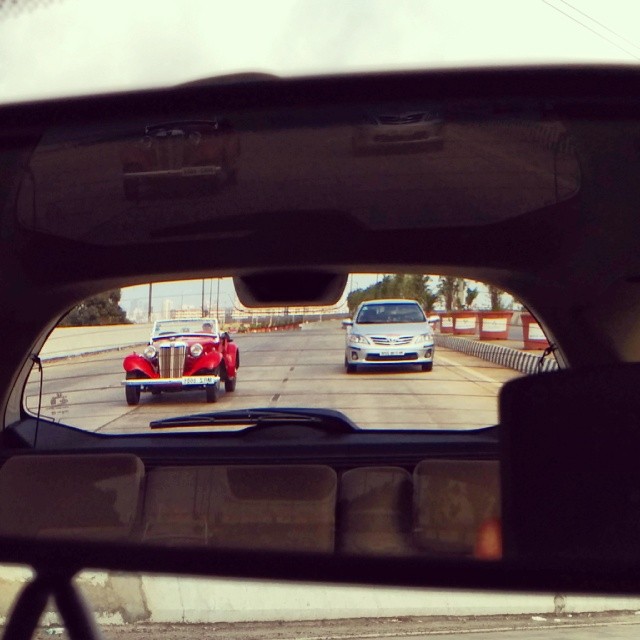 reflection in rear view mirror of old model cars on roadway