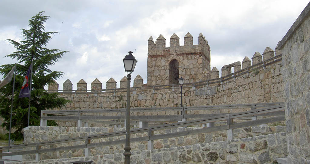 a tall tower next to a stone wall and light fixture