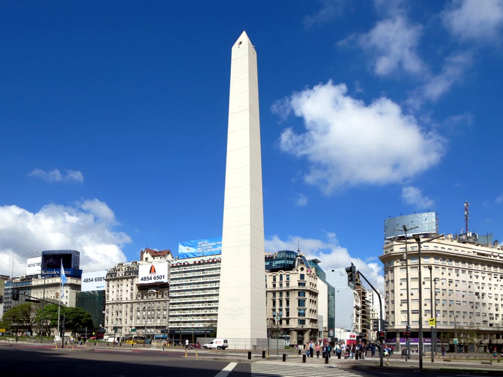 a big obelisk standing next to two tall buildings