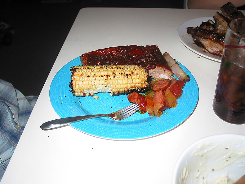 a plate of food with grilled corn and tomatoes