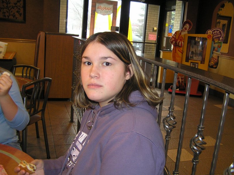 a girl sitting at a table with some food